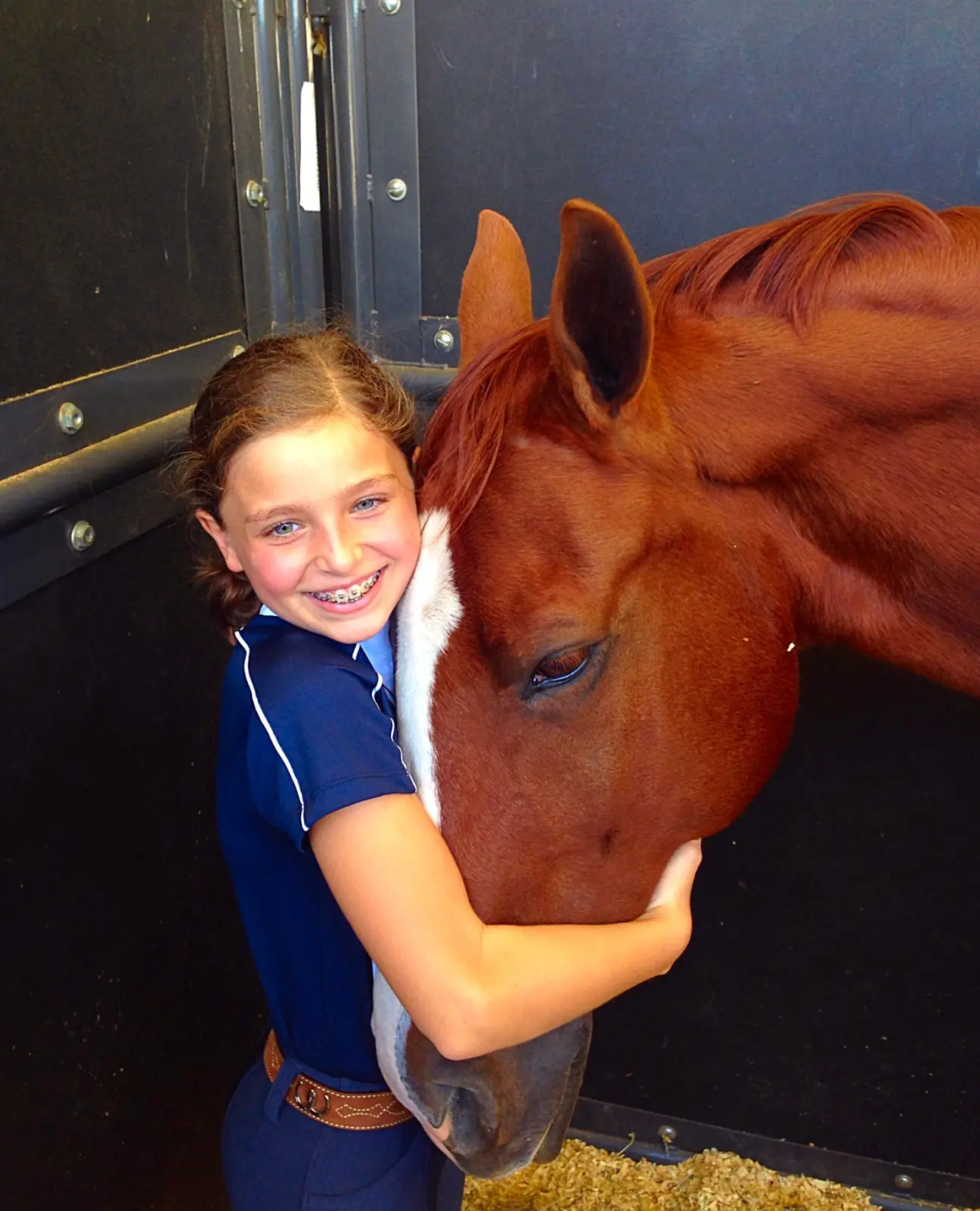 A young Sophia hugging her chestnut at the trailer